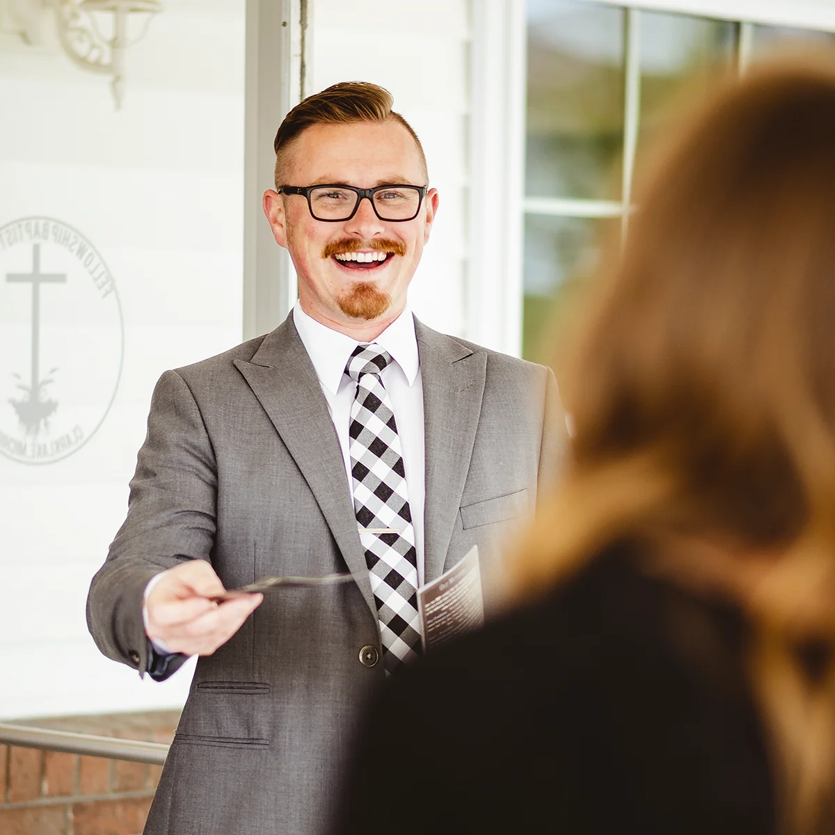 smiling pastor handing church member church bulletin